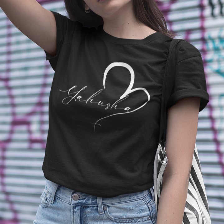 Woman wearing a black t-shirt with white text and light blue jeans in front of a graffiti-covered wall.
