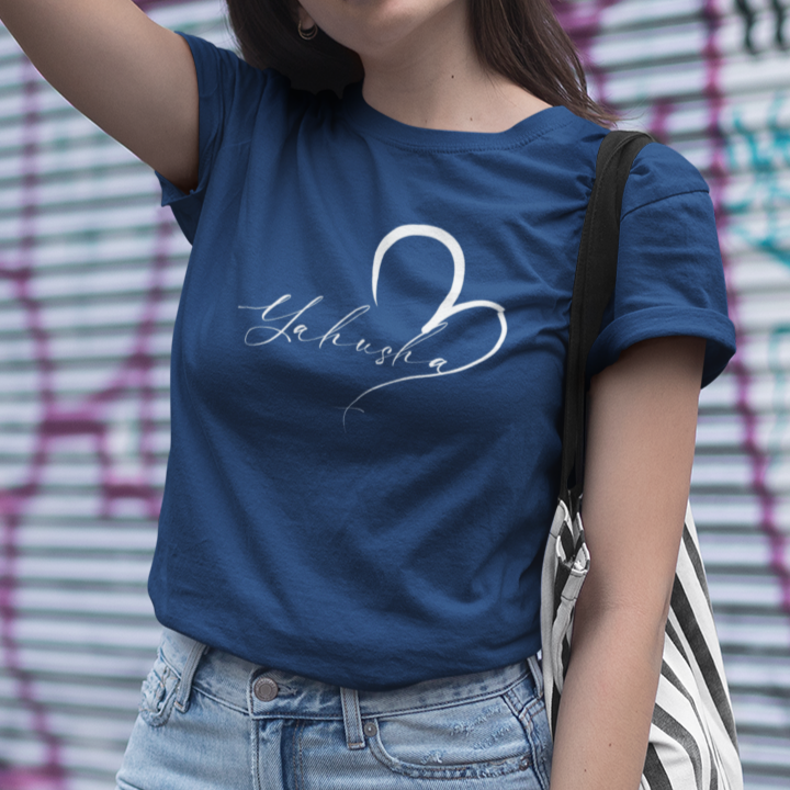 Woman wearing a blue t-shirt with text and light blue jeans in front of a graffiti-covered wall.