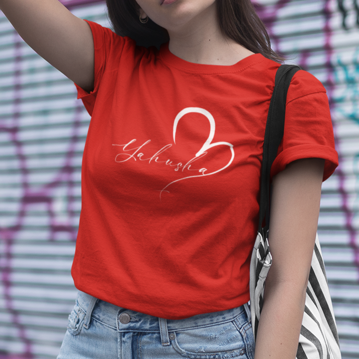 Woman wearing a red t-shirt with a white heart design in front of a graffiti-covered wall.