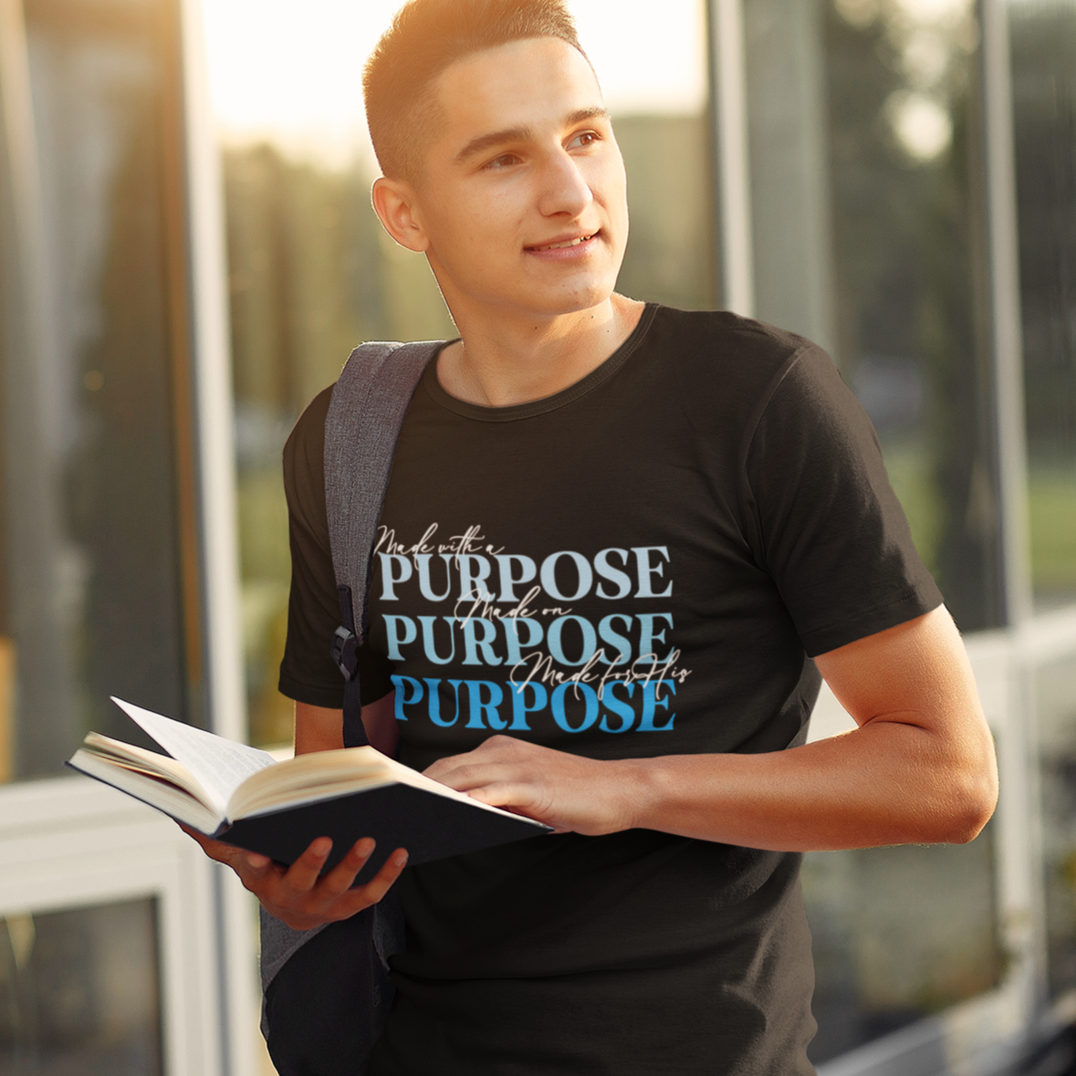 Man holding a book with 'PURPOSE' text, standing outdoors.