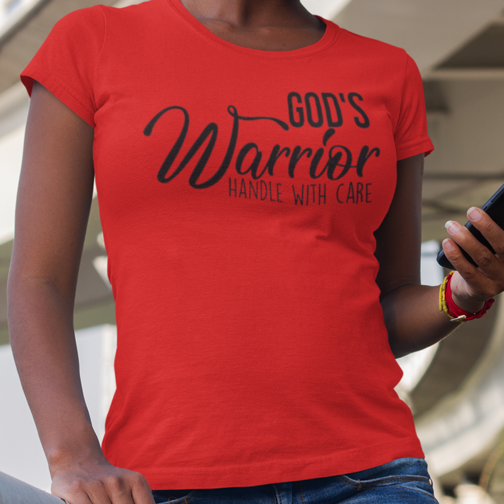 Person wearing a red 'God's Warrior' t-shirt using a phone under a bridge.