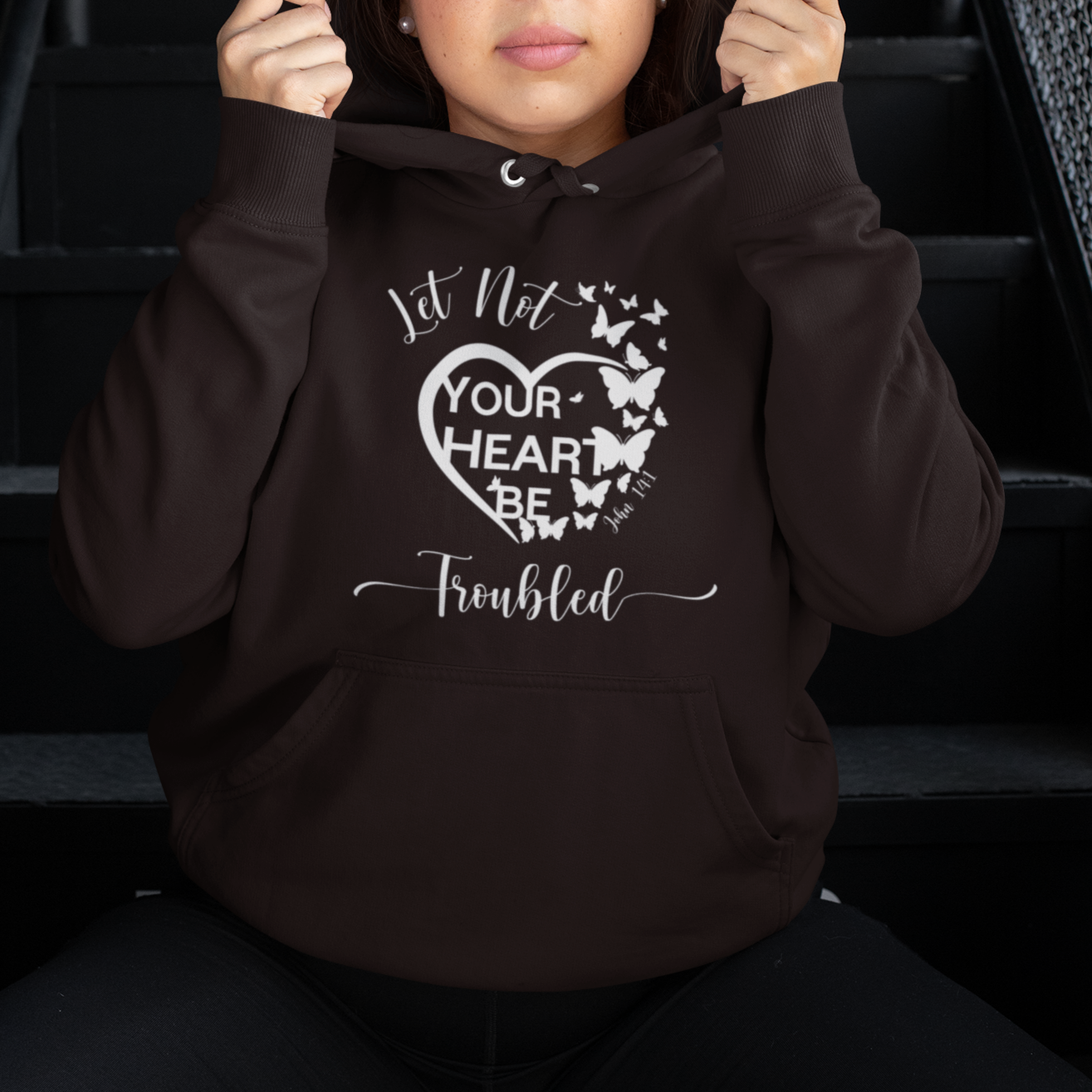 Person wearing a hoodie with text and butterfly design on stairs