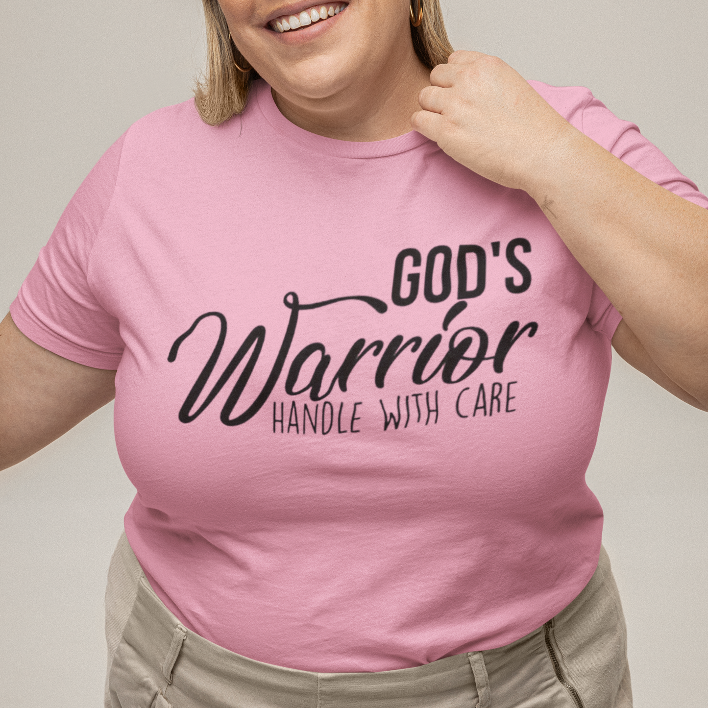 Person wearing a pink t-shirt with text, standing against a plain background