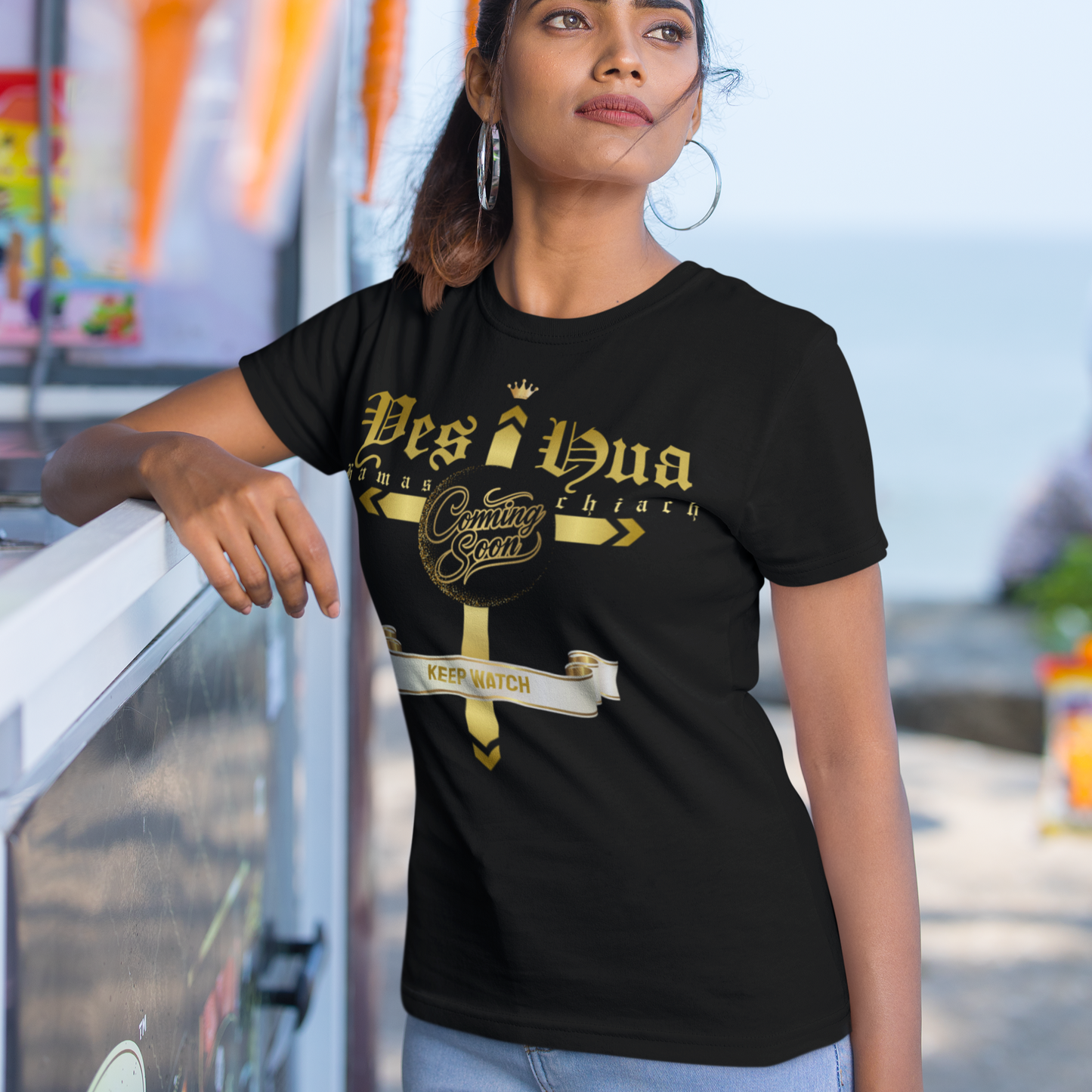 Woman wearing a black t-shirt with gold text, standing outdoors.