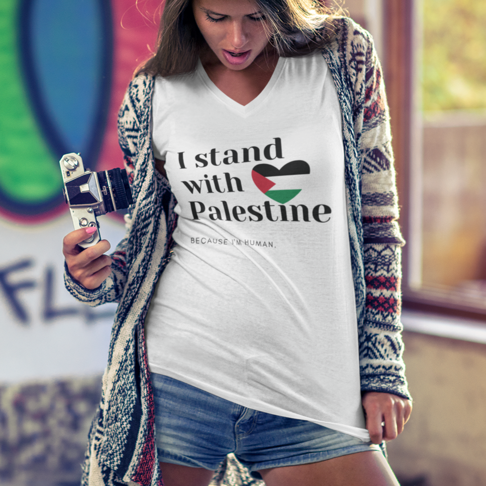 Woman wearing a 'I stand with Palestine' shirt in front of a colorful mural.