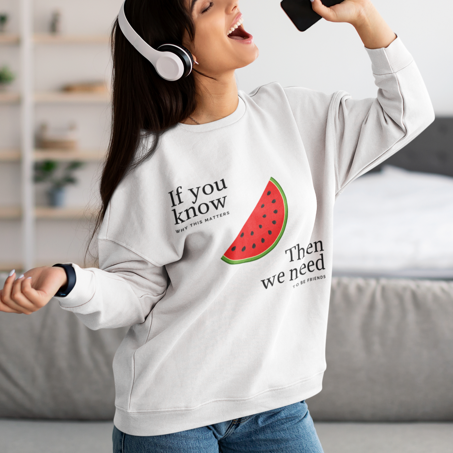 Woman wearing a sweatshirt with a watermelon design and text, listening to music.