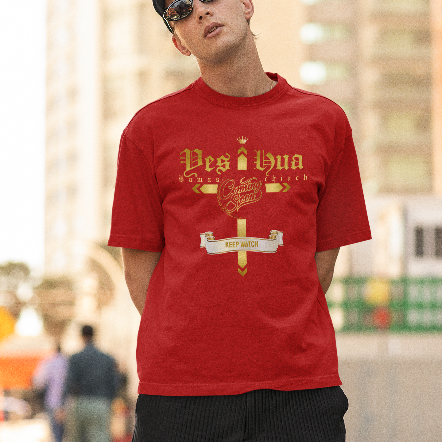 Man wearing a red t-shirt with gold text in an urban setting