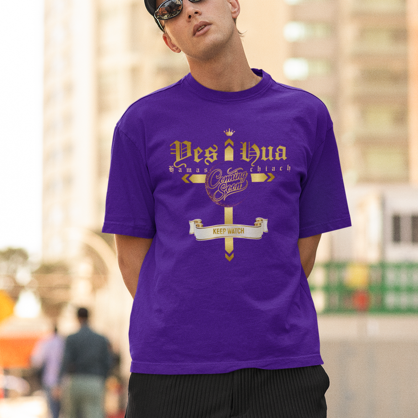 Man wearing a purple t-shirt with text and graphics, standing outdoors.