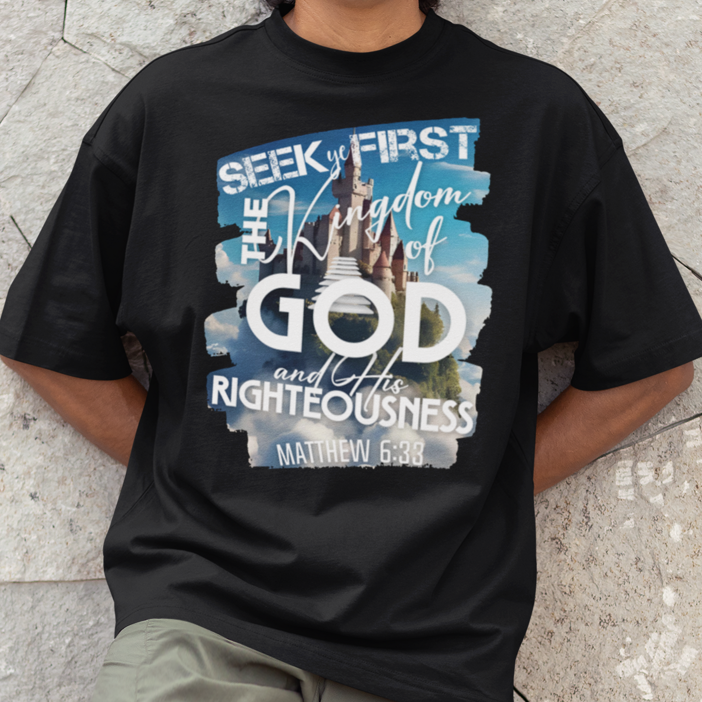 Man wearing a black t-shirt with a religious design on a stone pavement background