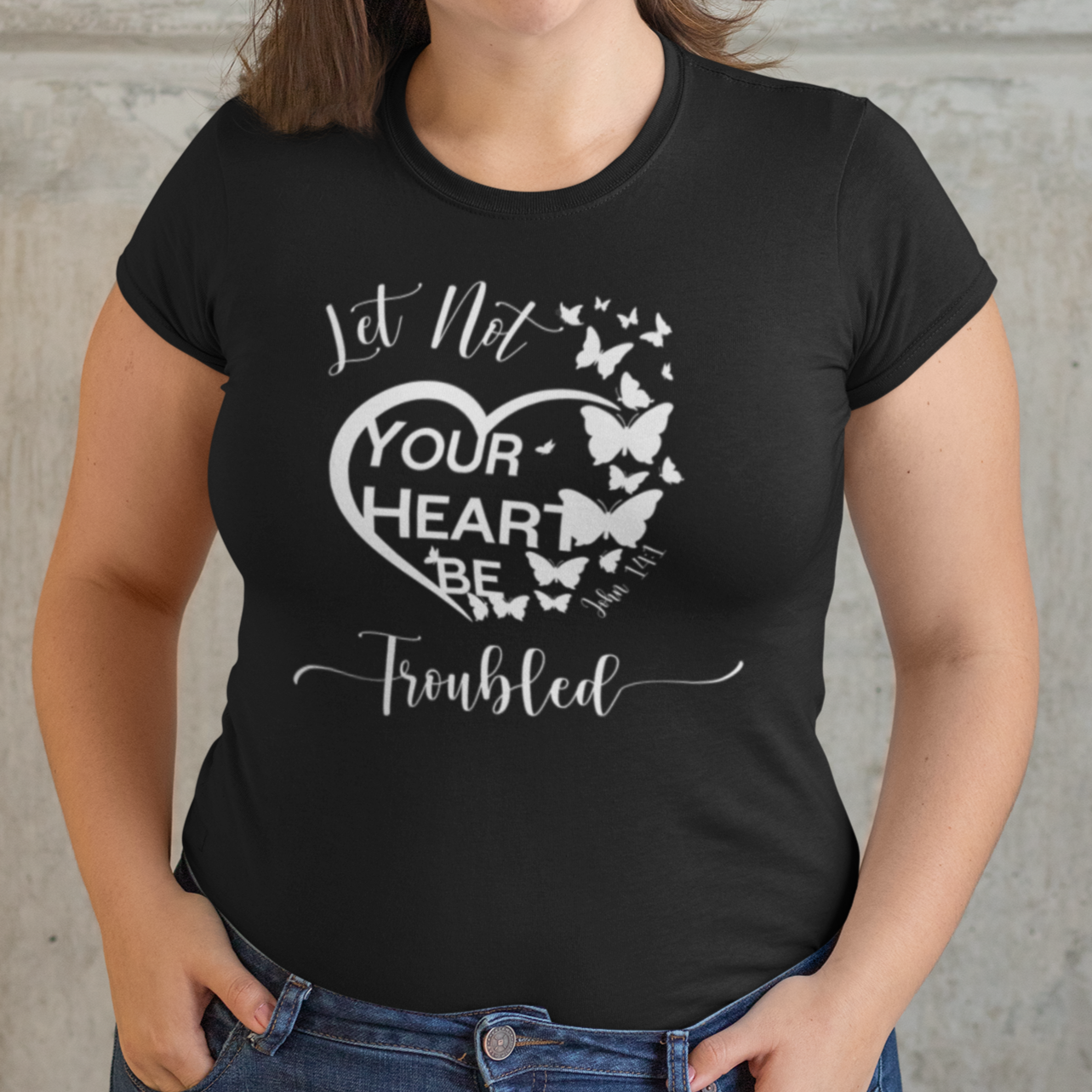 Woman wearing a black t-shirt with a heart design and text against a stone wall.