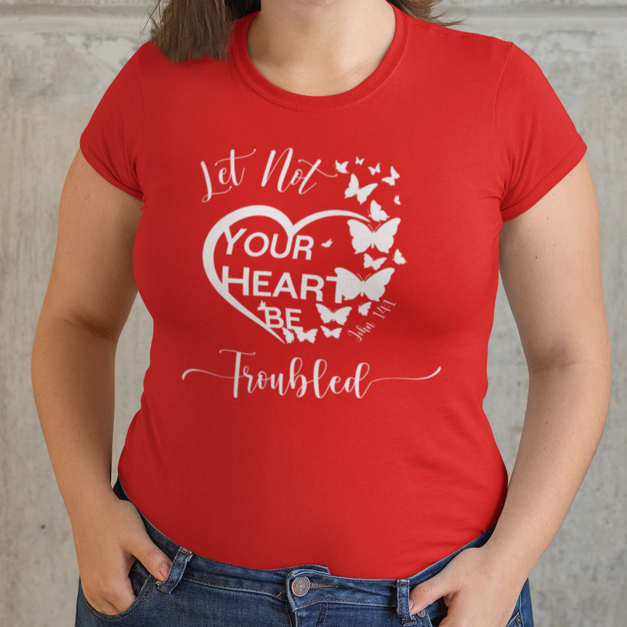 Woman wearing a red t-shirt with a heart design and text against a stone wall background