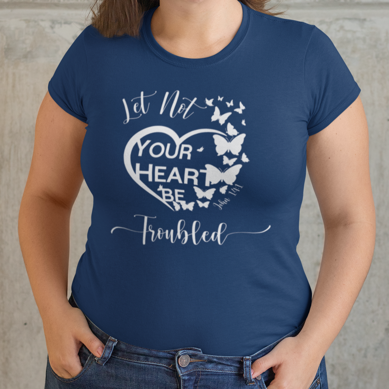 Woman wearing a blue t-shirt with a heart design and text against a stone wall.