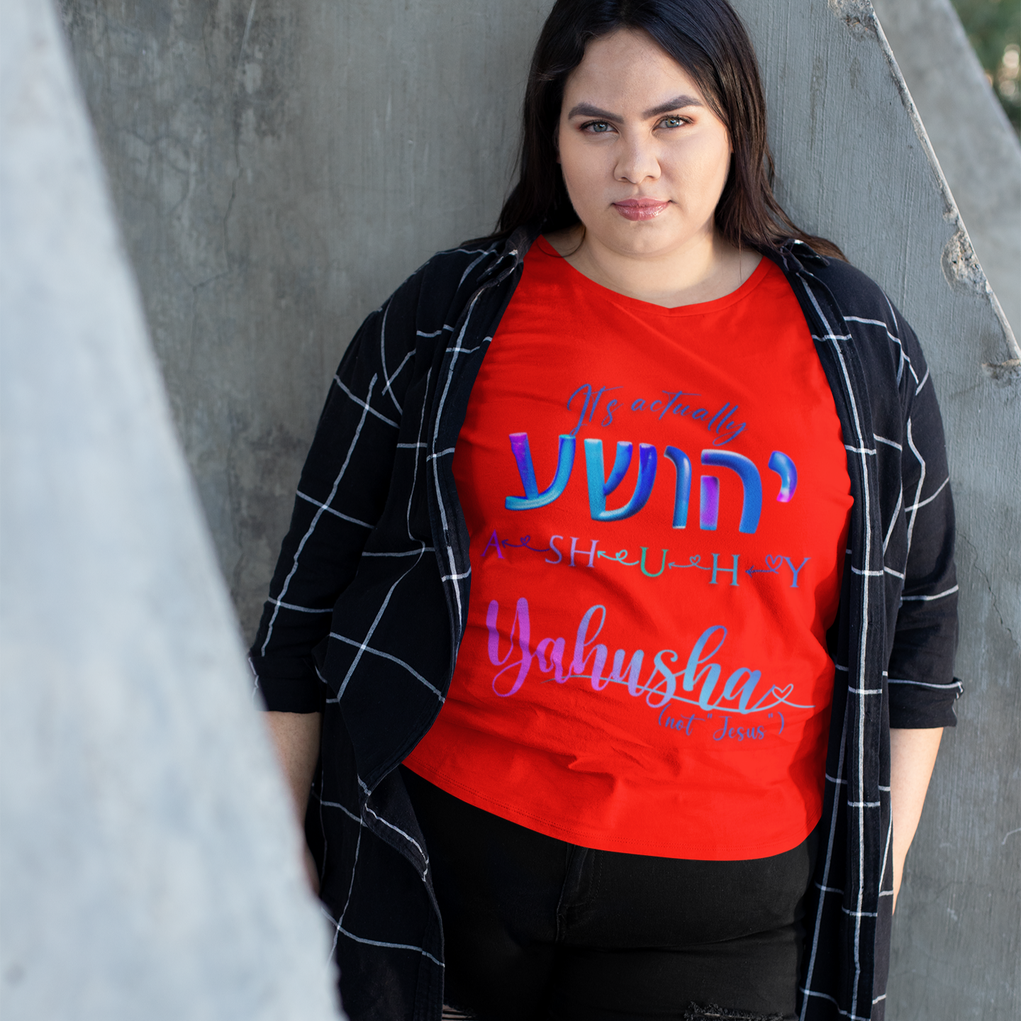 Person wearing a red shirt with text, standing against a concrete wall.