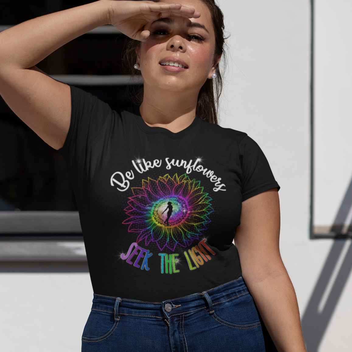 Woman wearing a black t-shirt with a colorful design and text, standing outdoors.