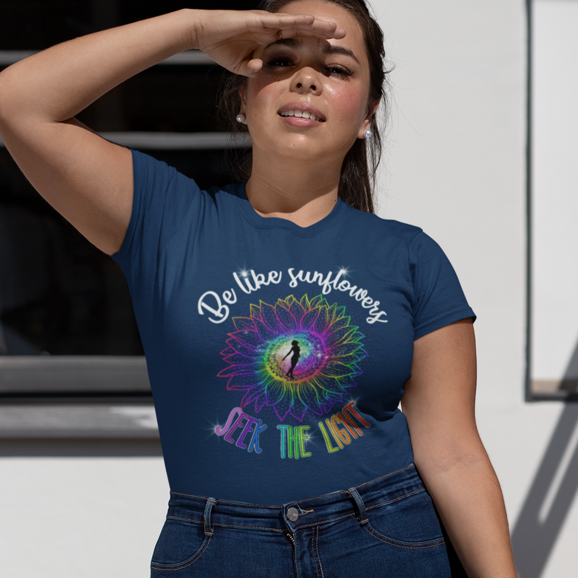 Woman wearing a blue t-shirt with a colorful design and text, standing outdoors.