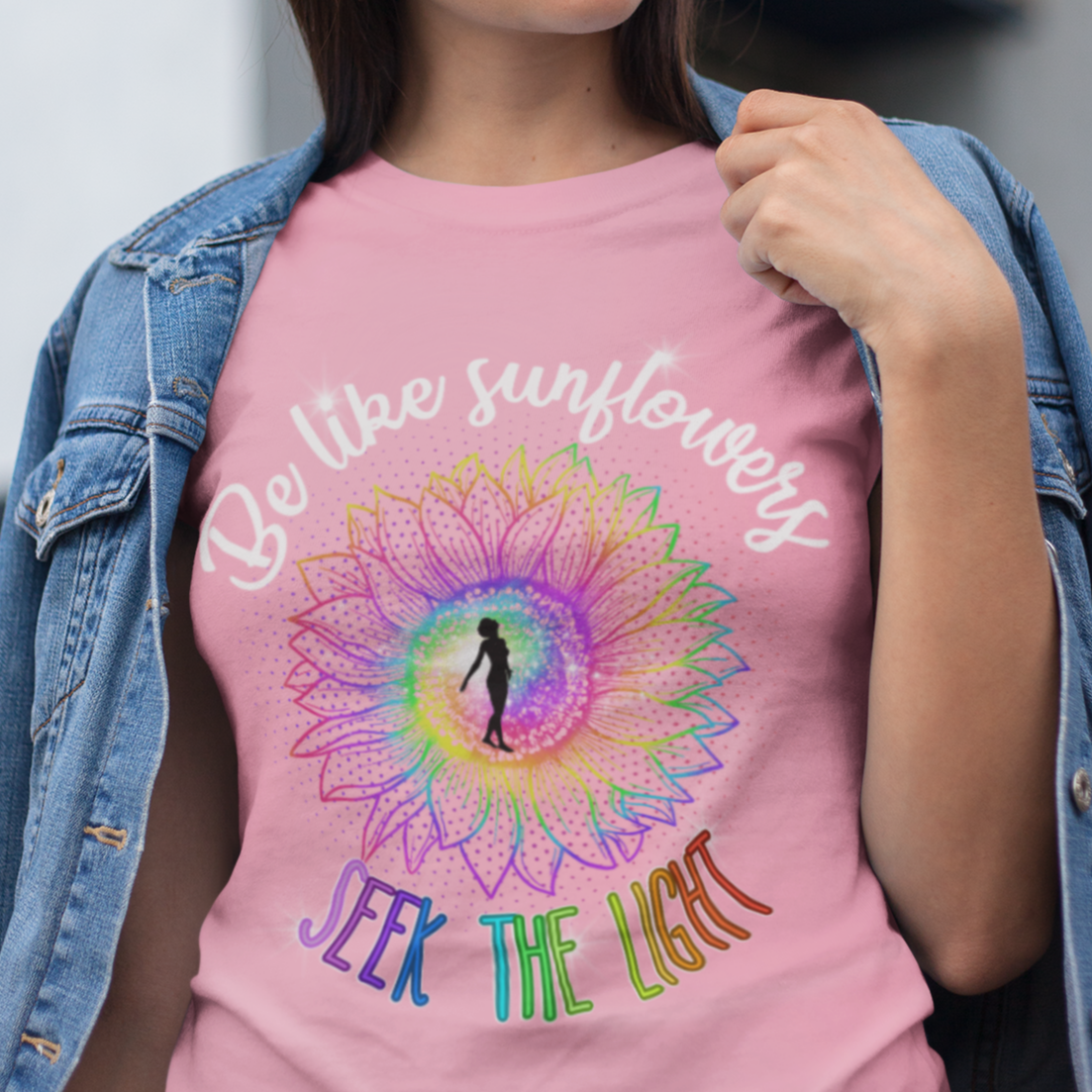 Woman wearing a pink t-shirt with a colorful design and text, standing outdoors.