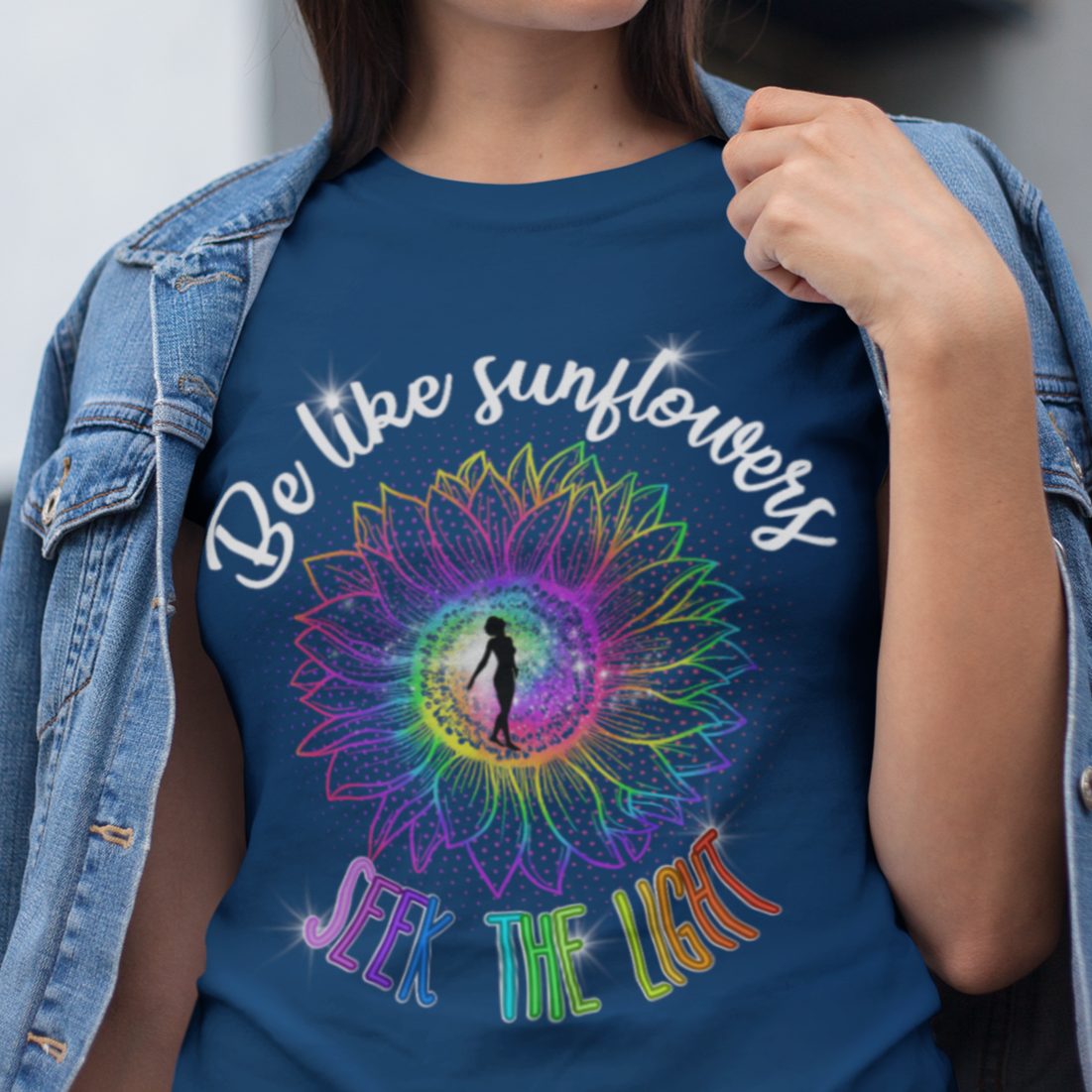 Woman wearing a blue t-shirt with a colorful design and text, standing outdoors.