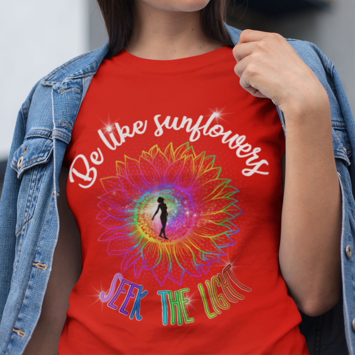 Woman wearing a red t-shirt with colorful design and text, standing outdoors.