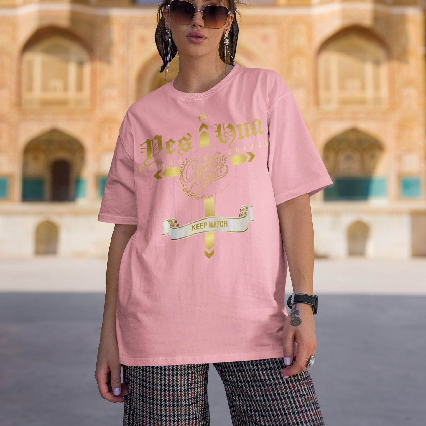 Woman wearing a pink t-shirt with text and graphics in front of an architectural building.