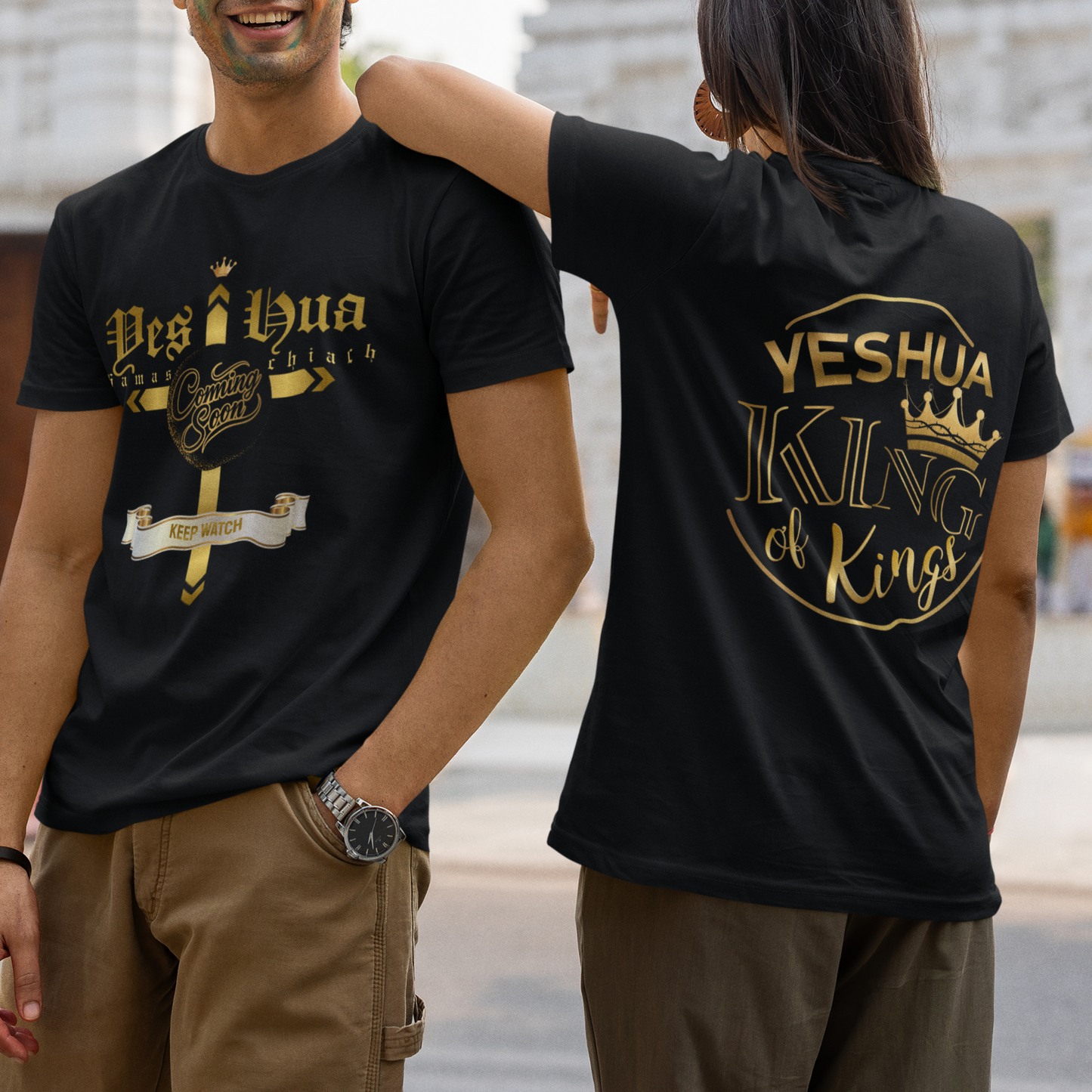 Two people wearing black t-shirts with gold text and designs, standing in front of a temple.