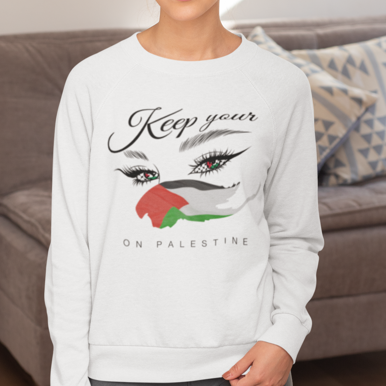 Woman wearing a white sweatshirt with a graphic design in a living room.