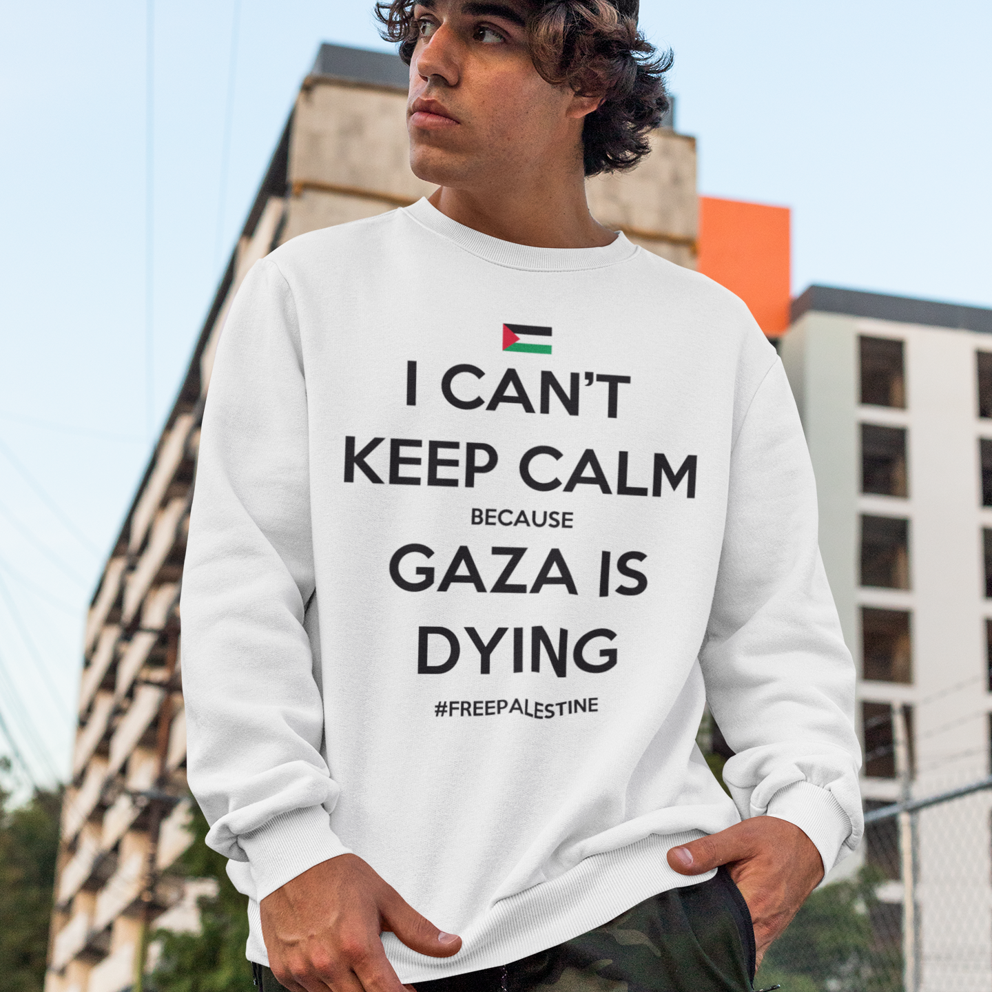 Person wearing a white sweatshirt with a message about Gaza, standing outdoors.
