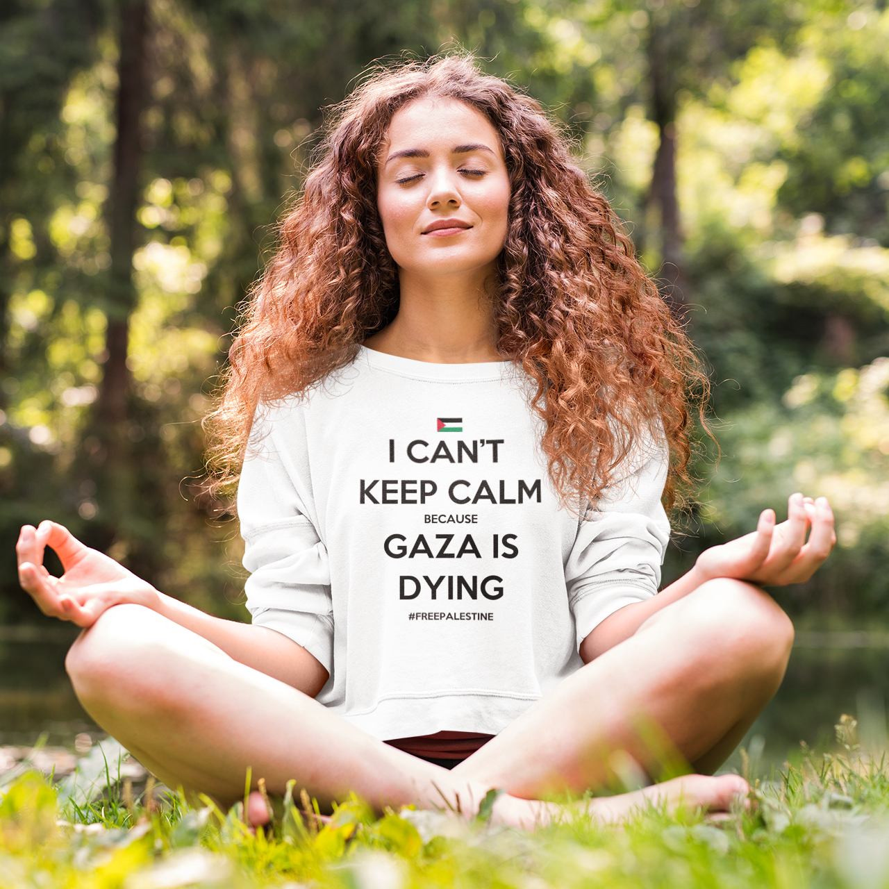 Woman meditating outdoors wearing a shirt with a message.