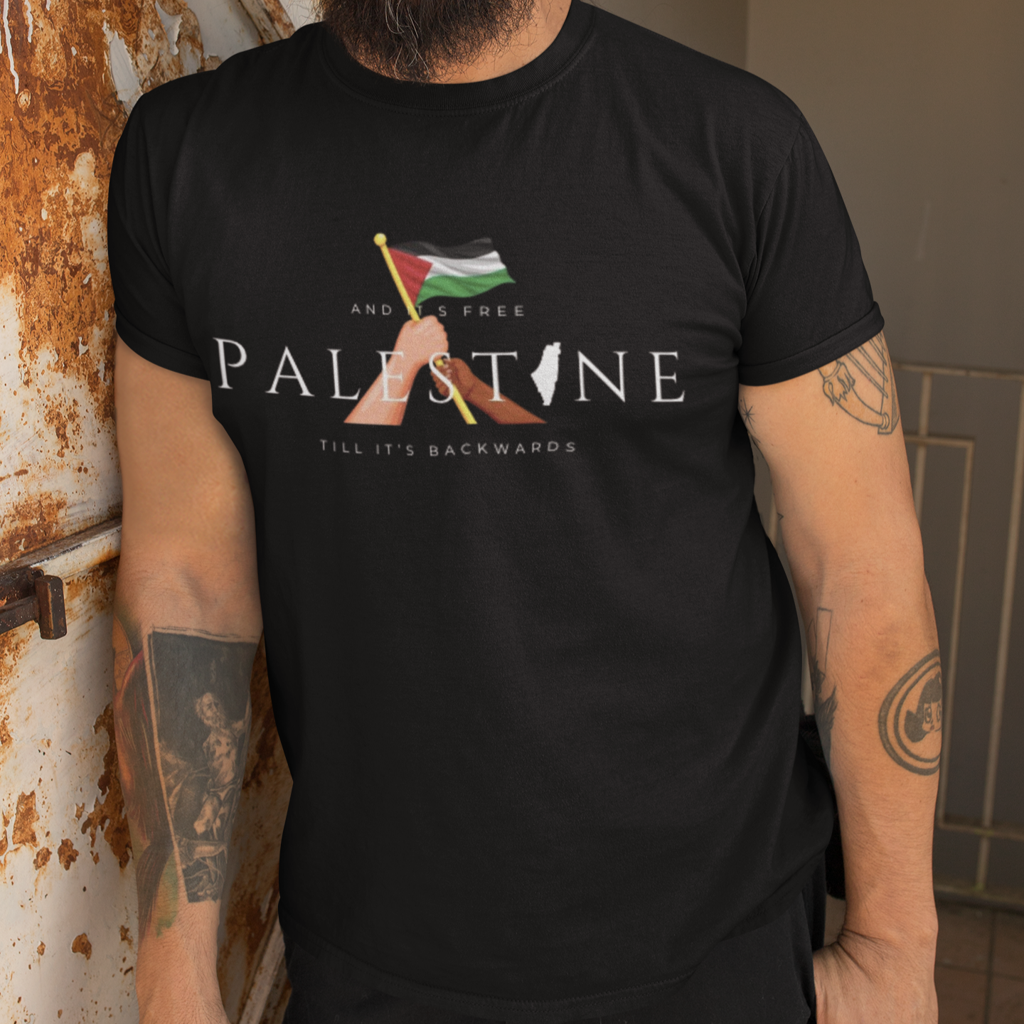 Man wearing a black t-shirt with a graphic design and text, standing against a wall.