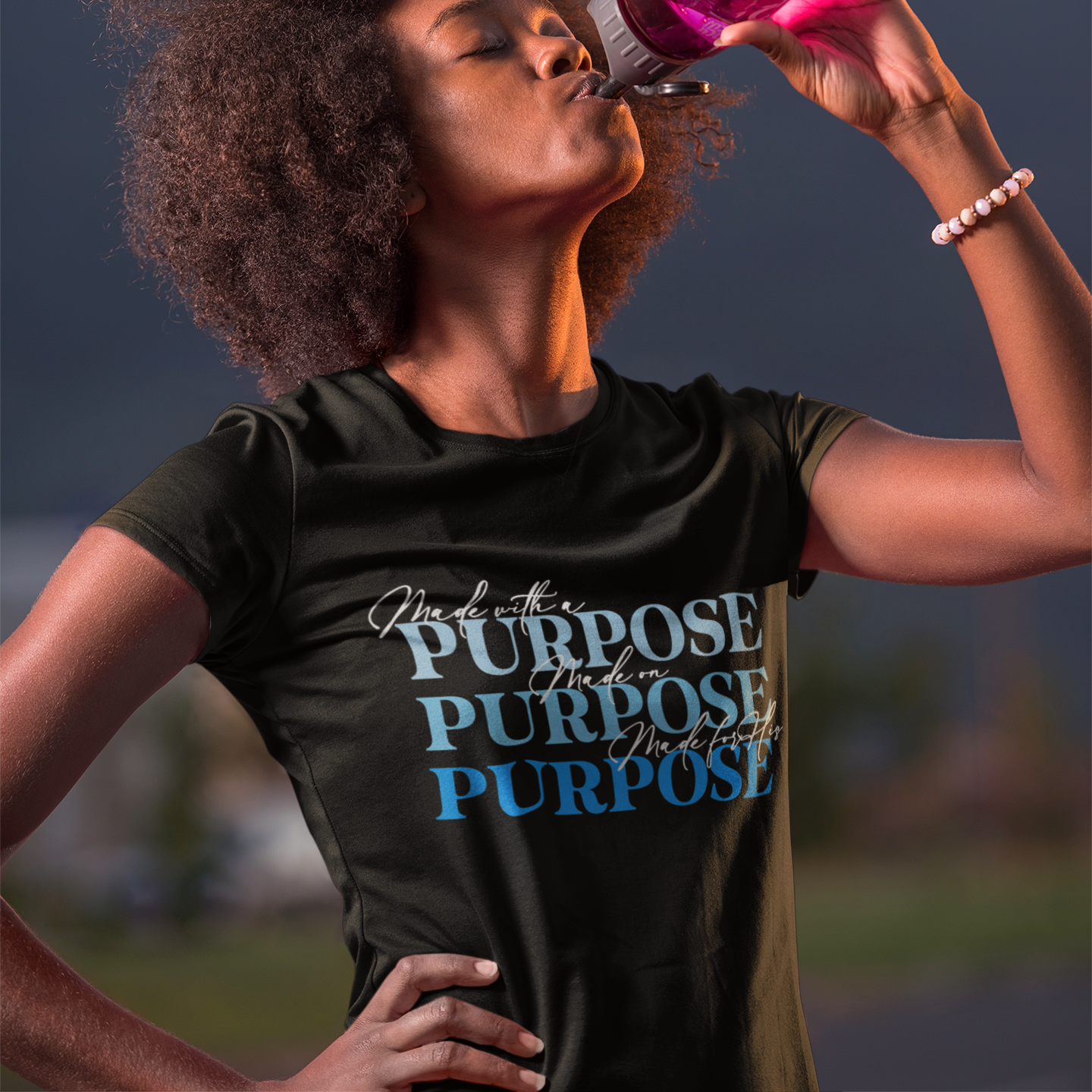 Person drinking from a pink water bottle with a scenic background