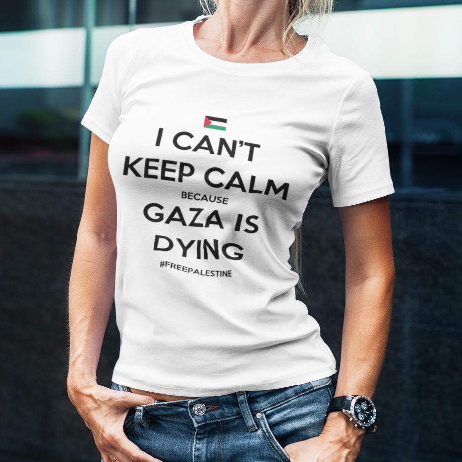 Person wearing a white t-shirt with a message about Gaza, standing in front of a modern building.