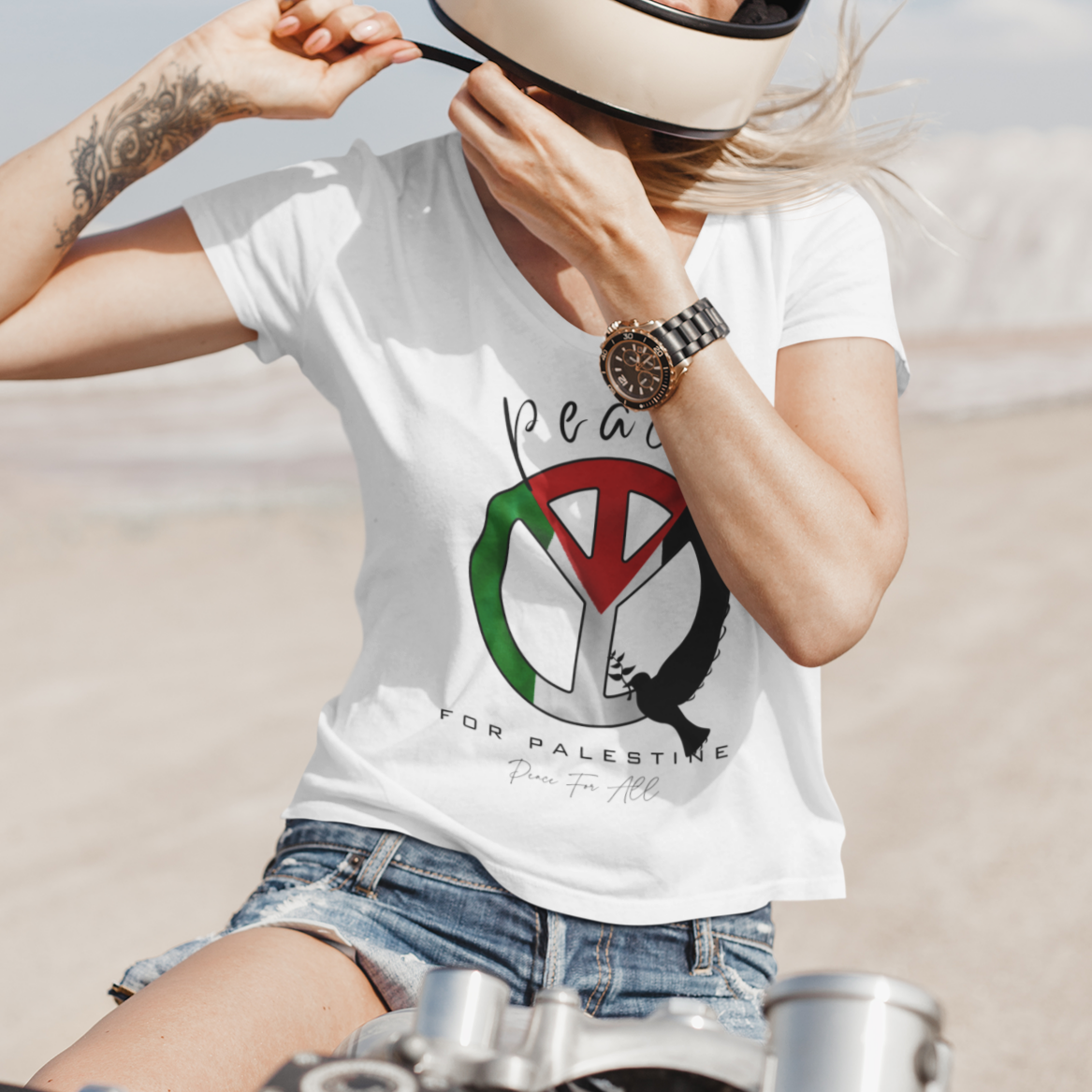 Person wearing a white t-shirt with a graphic design, sitting on a motorcycle in a desert setting.