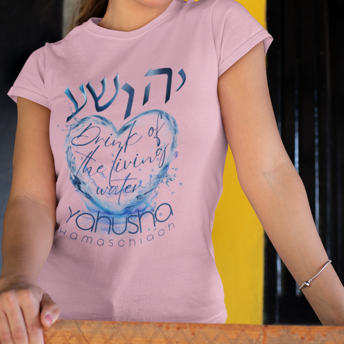 Woman wearing a pink t-shirt with text and design, holding a wooden object.