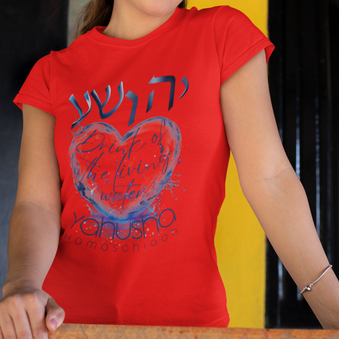 Woman wearing a red t-shirt with a graphic design, standing against a dark background.