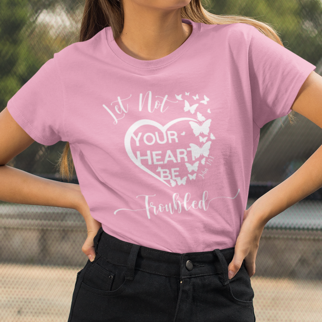 Person wearing a pink t-shirt with a graphic design and text, standing outdoors.