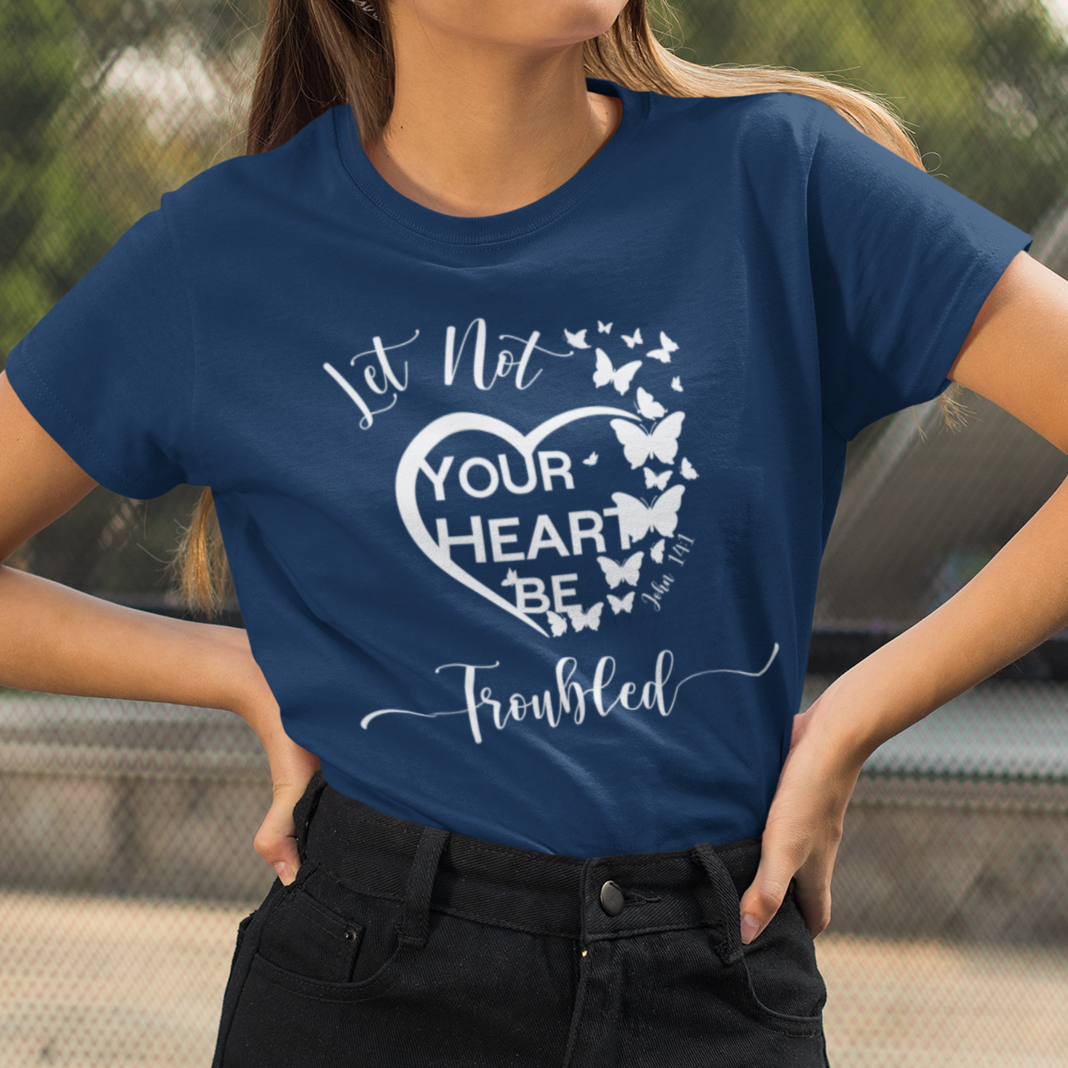 Woman wearing a blue t-shirt with a heart design and text outdoors.