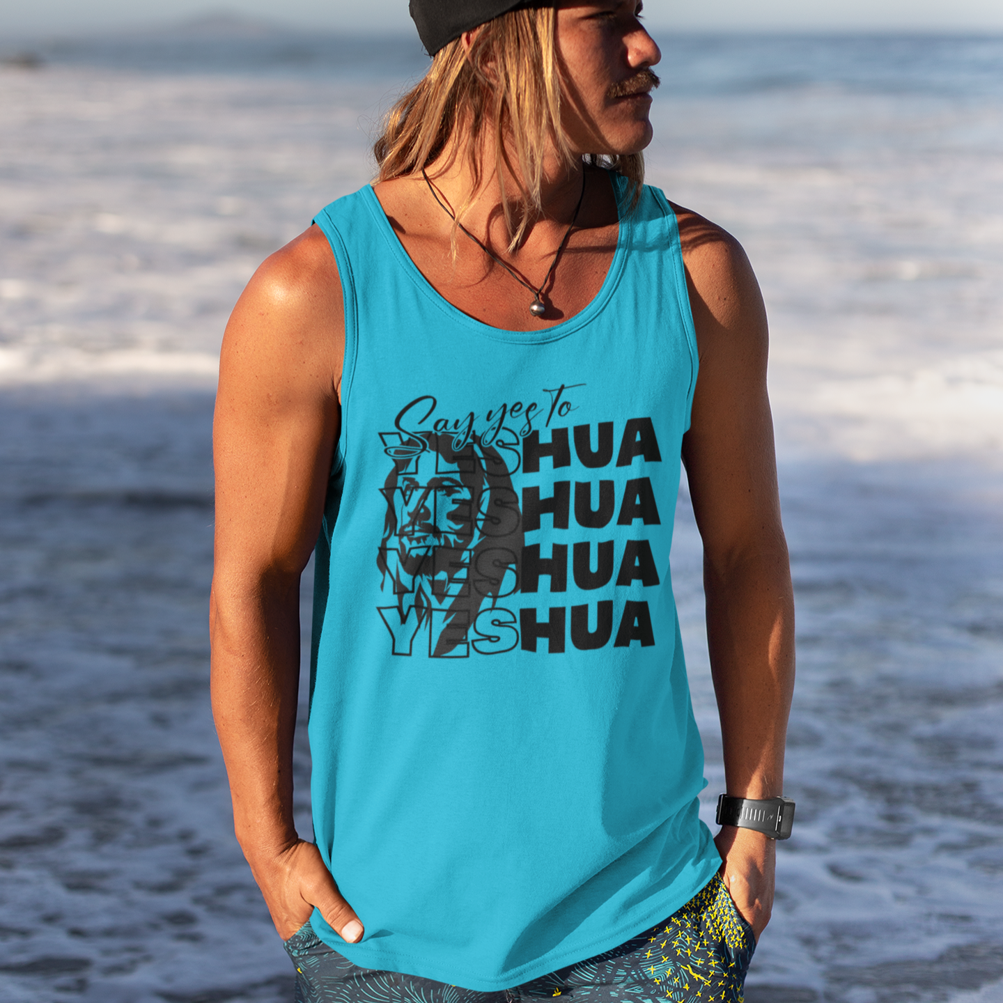 Person wearing a blue tank top with text and graphics, standing on a beach.