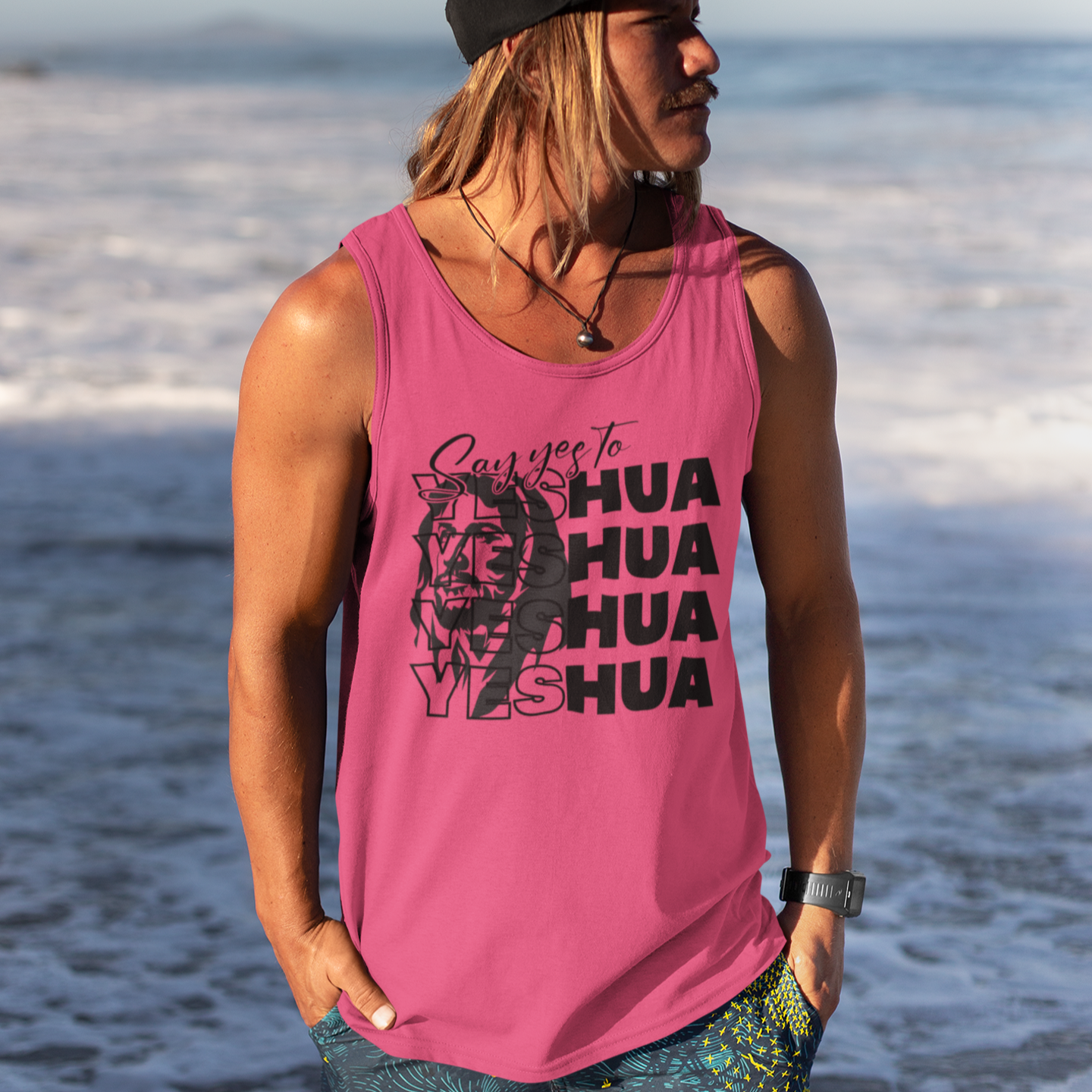 Person wearing a pink tank top with text and graphics on a beach