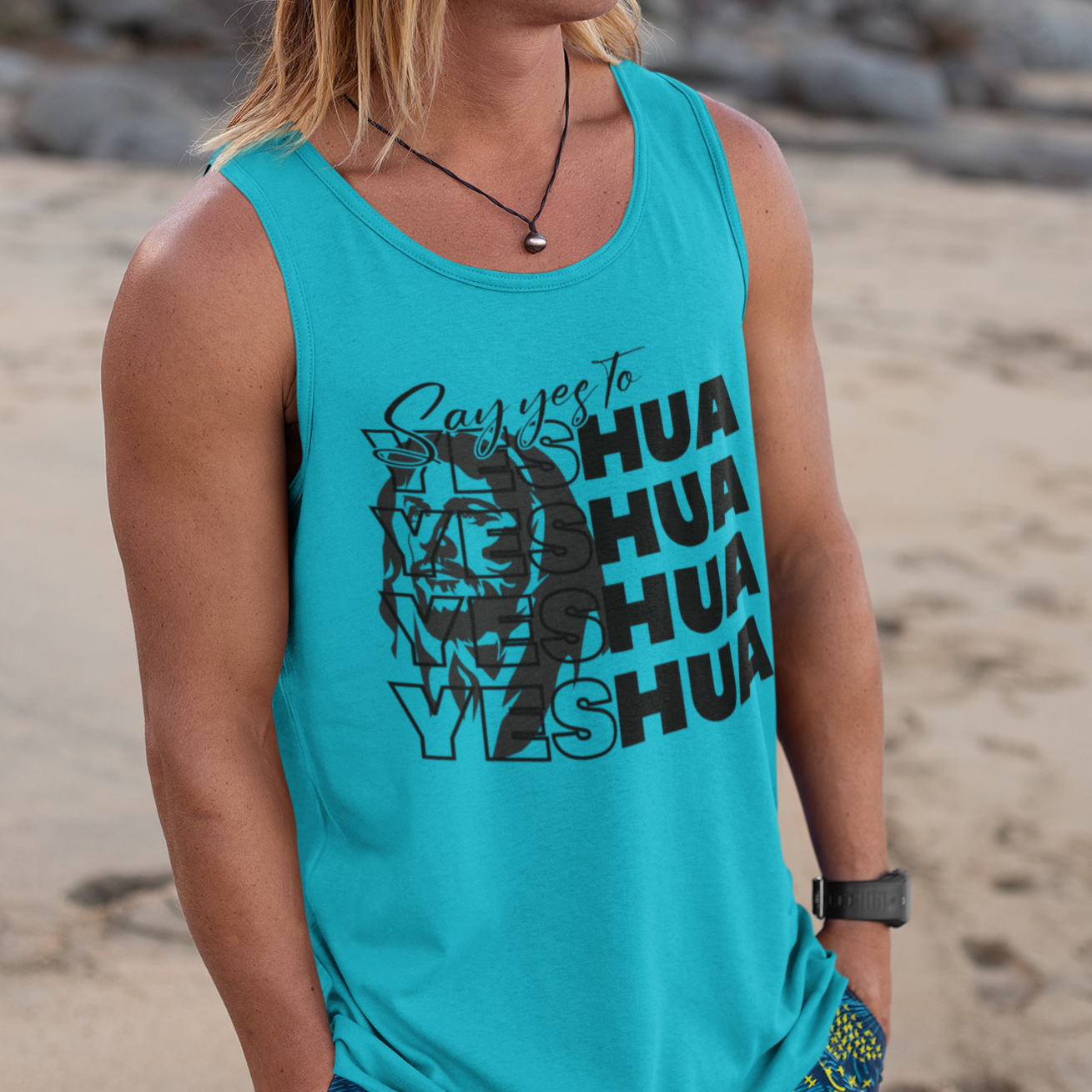 Man wearing a turquoise tank top with text and graphics on a beach