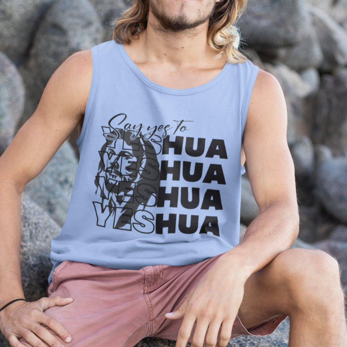 Man sitting on rocks wearing a tank top with text and graphics.
