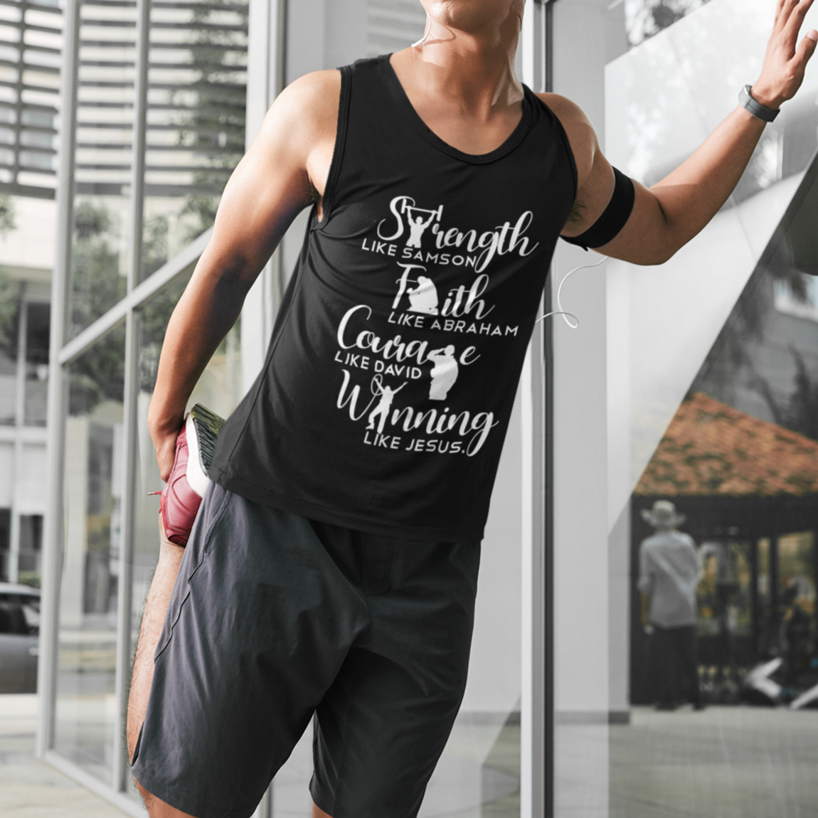 Man wearing a black tank top with motivational text, standing in an urban setting.