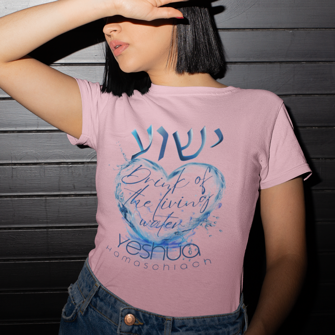 Person wearing a pink t-shirt with a blue heart design and text against a dark wooden background