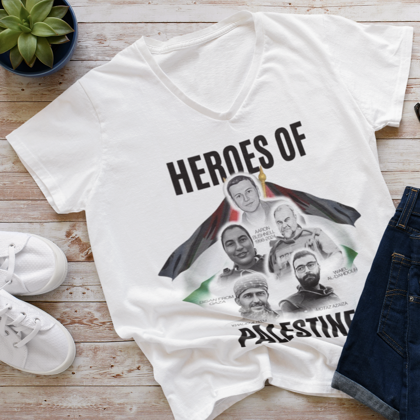 White t-shirt with 'Heroes of Palestine' graphic on a wooden surface with shoes and sunglasses.