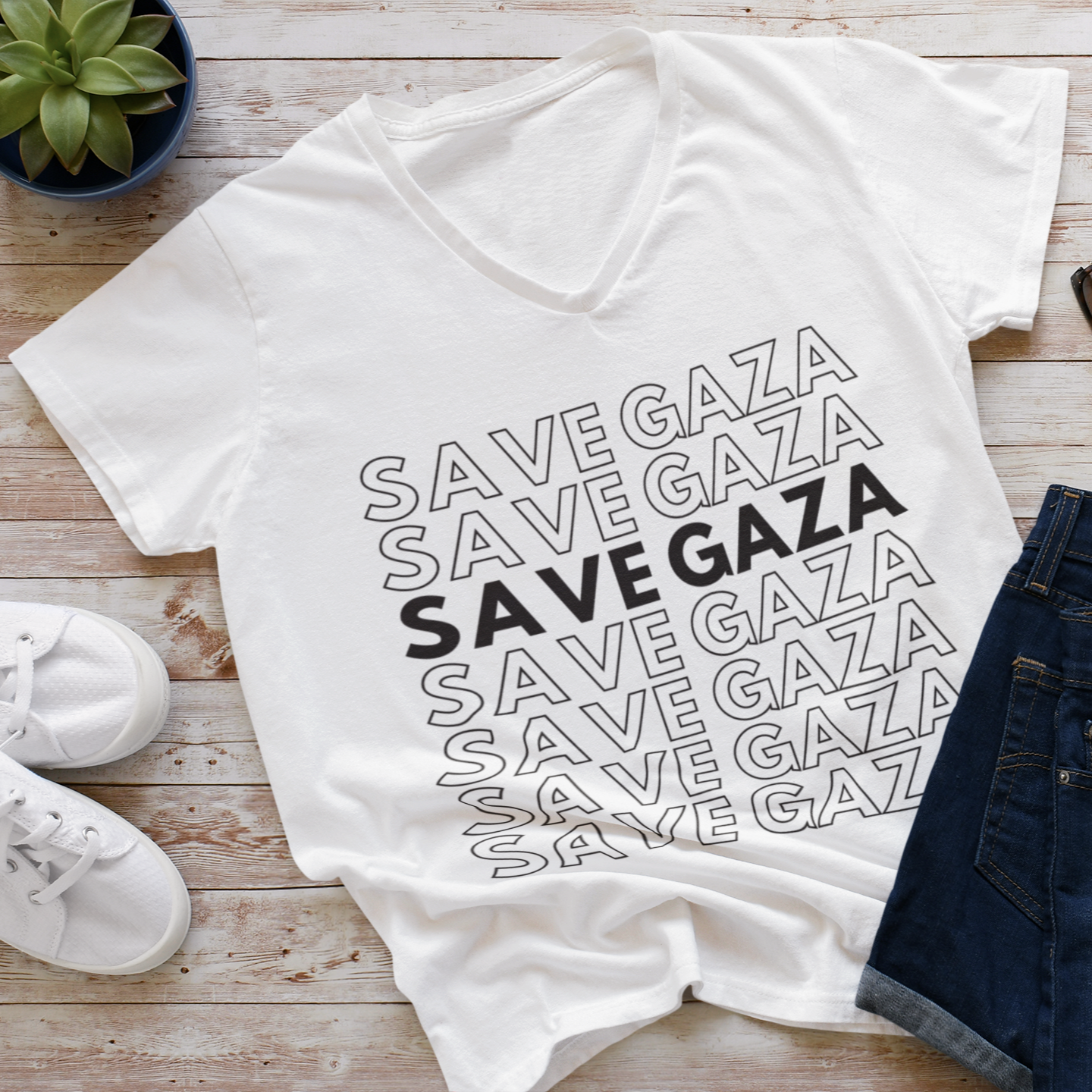 White t-shirt with 'SAVE GAZA' text on a wooden surface with shoes and jeans.