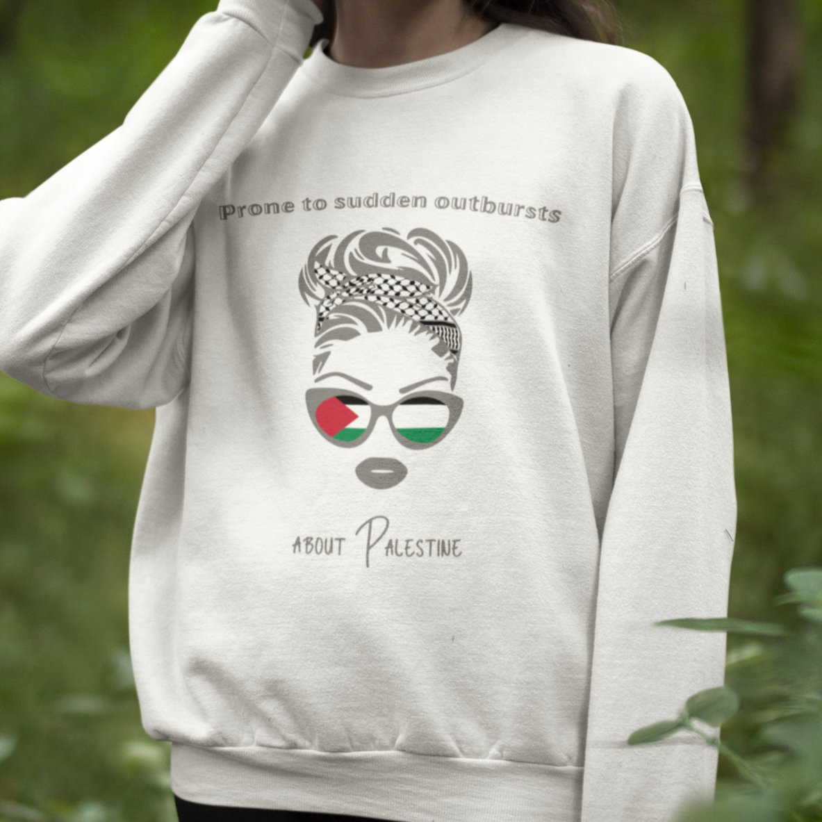 Woman wearing a white sweatshirt with a graphic design in a forest setting