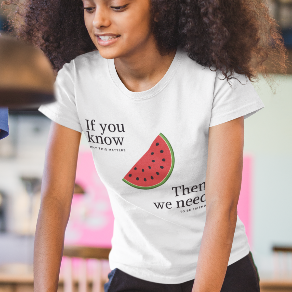 Person wearing a white t-shirt with a watermelon graphic and text in a casual setting.
