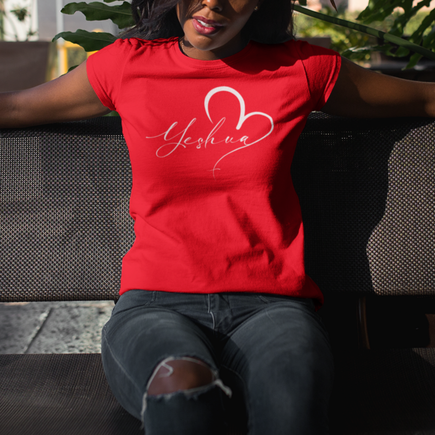 Woman wearing a red t-shirt with a logo, sitting on a bench outdoors.
