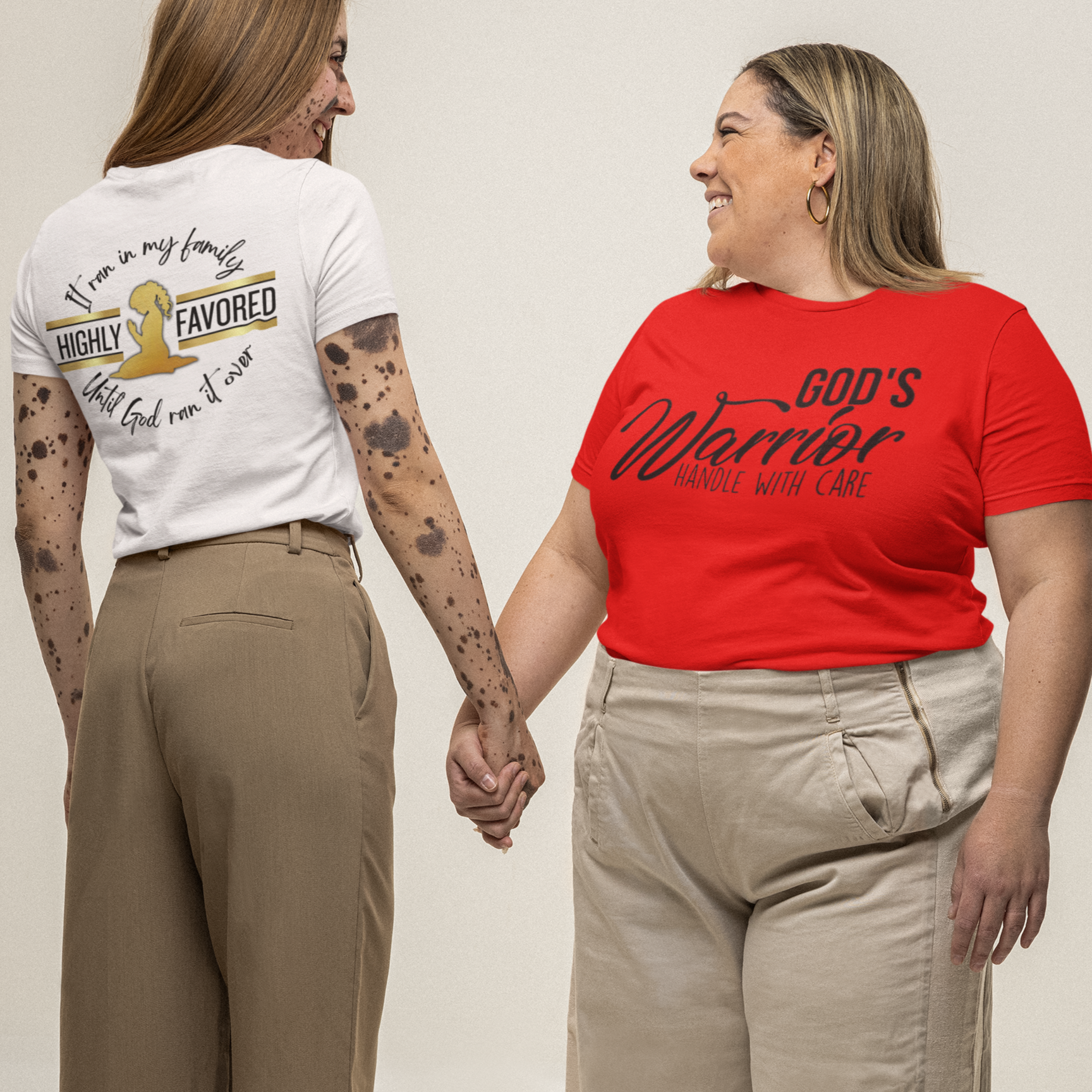 Two women holding hands, wearing t-shirts with text and graphics.