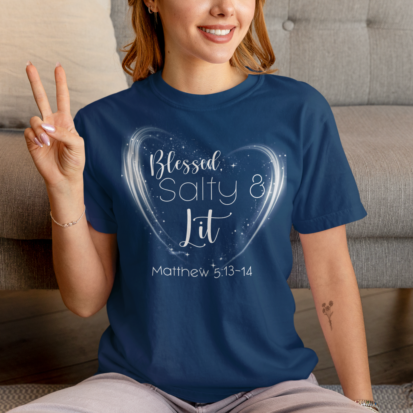 Person wearing a blue t-shirt with a heart design and text, sitting on the floor.