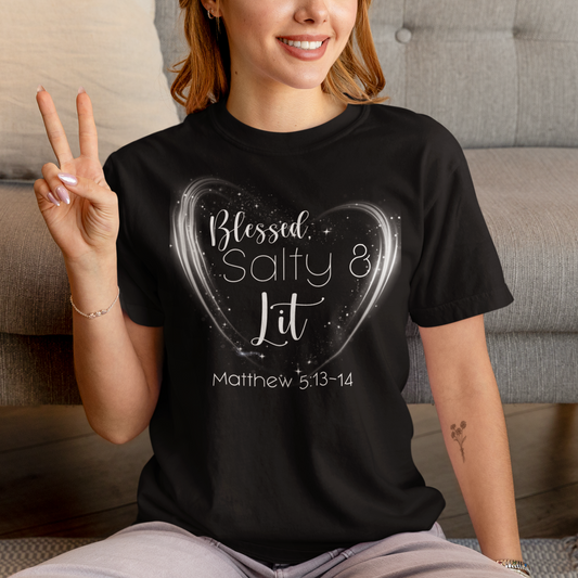 Person wearing a black t-shirt with 'Blessed, Salty & Lit' text, sitting on a couch.