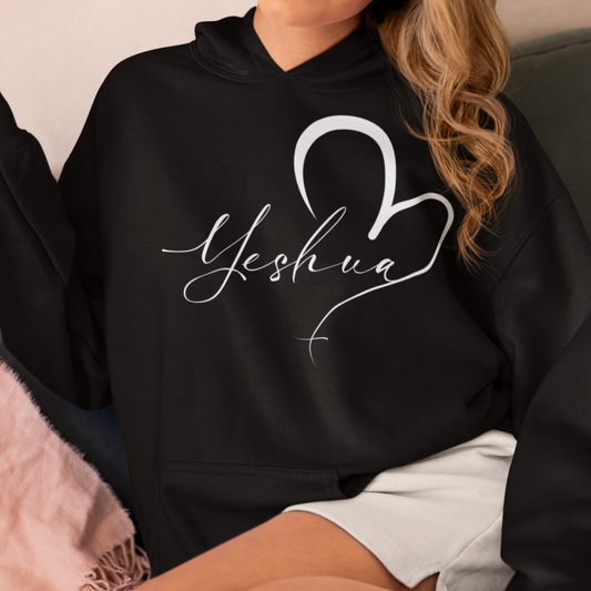 Person wearing a black hoodie with 'Yeshua' and a heart design.